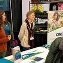 A group of people stand behind a booth at a tradeshow.