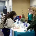 Students receive guidance from another student at a student recource fair.