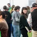 A college student smiles as she talks to an exhibitor at a career fair.