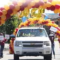 Graduate driving through an archway of balloons at Grab Fest 