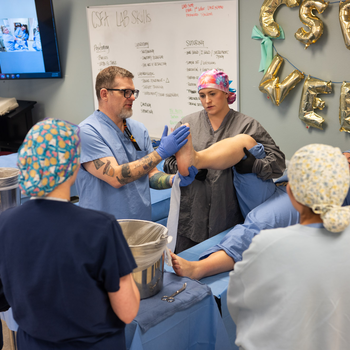 An instructor teaches proper methods for applying a cast on a patient.