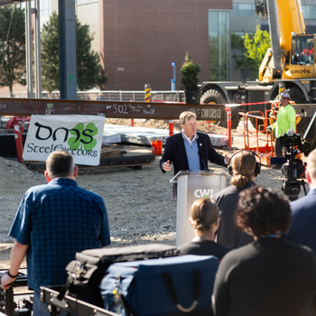 An audience listens to President Gordon Jones during a ceremony marking a construction milestone.
