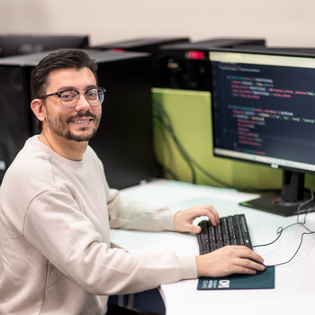 A software development student sits for a portrait at a computer.