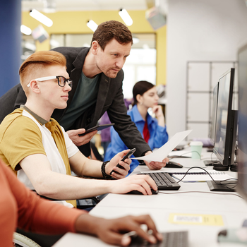 A teacher helps a student at a computer.