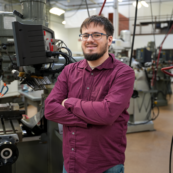 Student stands in front of machine tool technology equipment