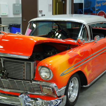 Red Antique car with yellow-orange flames and white top.