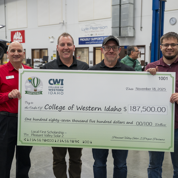 Four people standing together holding a check