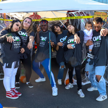 Students dressed in Halloween costumes pose in front of a table with candy on it.