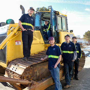 Heavy Equipment Technician students standing in front of bulldozer