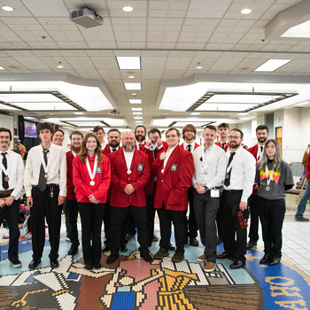 College students pose for a group photo wearing medals that were won during a competition.