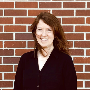 A photo of a woman against a brick wall.
