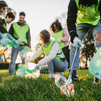Students volunteer in a park by picking up trash.