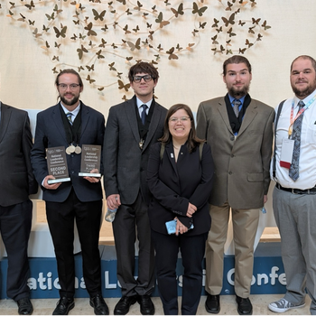 Students pose for a photo holding awards.