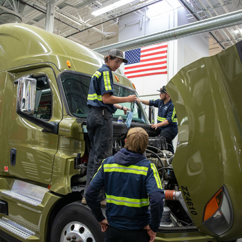 Students stand on the body of a semi truck as they learn about diesel engines.