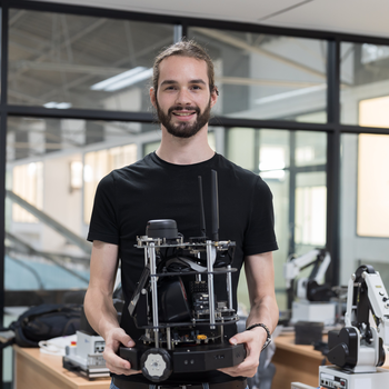 Man holding mechatronics equipment and smiling at the camera