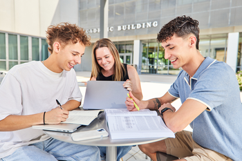 Students studying together at a table outside a campus building