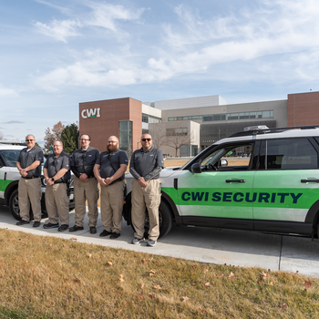 Security team members posing next to a patrol SUV on campus.