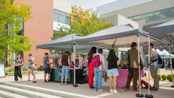 Students visiting club tables outside a campus building during Club Fest