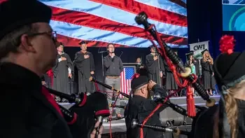 Stage and bag pipe players at a commencement ceremony during the national anthem