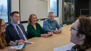 team meeting in a conference room engaged in conversation around a table