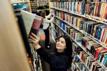 Student putting a book on a shelf in the library