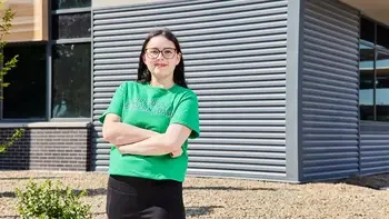 Student standing looking at the camera posing for a photo outside a campus building
