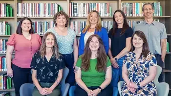 CWI Library staff posing in front of a shelf of books