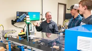 CWI students in an Advanced Mechatronics Engineer class with an instructor looking at a piece of equipment.
