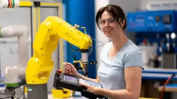 Student working in a mechatronics lab smiling at the camera