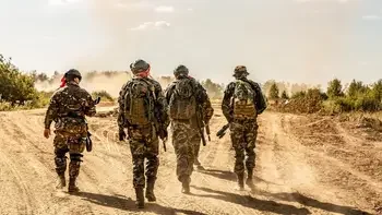 Group of solders walking on dirt road.