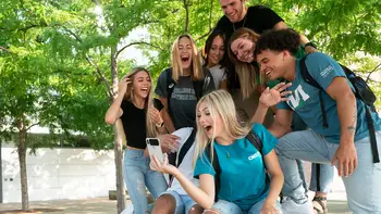 Group of students outside a campus building taking a selfie together. 