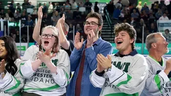 Group of individuals cheering at a sporting event wearing CWI jerseys