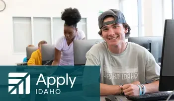 Student in a computer lab with other students looking at the camera and smiling