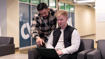 Staff helping a student working on a laptop