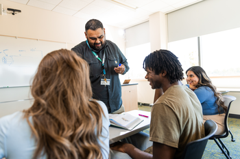 Faculty conversing with students in a classroom