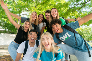 students posing for a photo outside a campus building