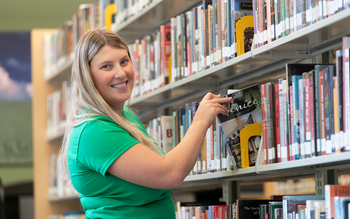 Student pulling book off book shelf