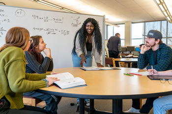 Math tutor helping students around a table