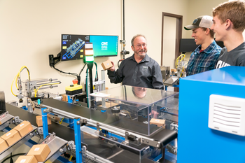 CWI students in an Advanced Mechatronics Engineer class with an instructor looking at a piece of equipment.