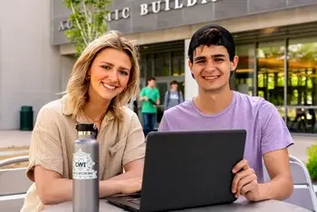 Students with laptop outside the Academic building
