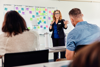 Instructor teaching a class in front of white board full of sticky notes