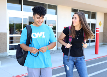 students exiting a campus building wearing backpacks