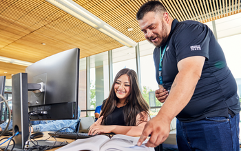 Digital Navigator helping a student at a computer in the computer lab