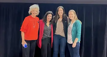 Four women smiling and posing for a photo on a stage