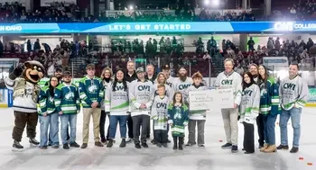 A group photo on the ice at a hockey game for a ceremonial scholarship check presentation.
