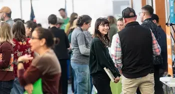 A college student smiles as she talks to an exhibitor at a career fair.
