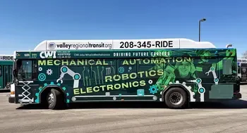 A city bus is parked and covered in a vinyl wrap featuring students and graphics.