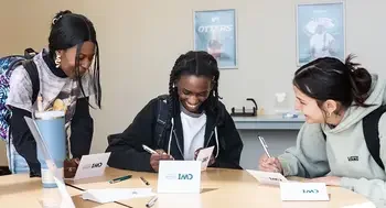Students smile as they sit at a table filling out thank you cards.