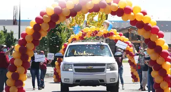 Graduate driving through an archway of balloons at Grab Fest 