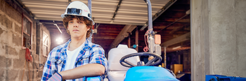 Student in hard hat next to farm equipment